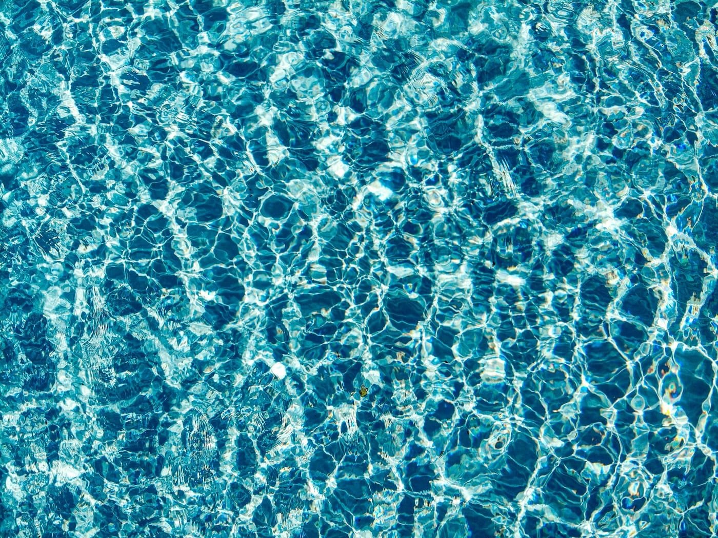 Reflexos de luz na água azul e transparente de uma piscina