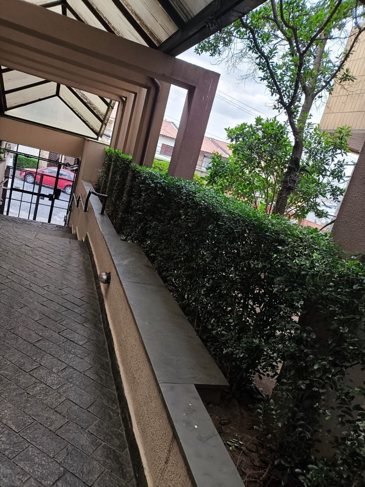 Cerca-viva aparada ao longo da rampa coberta de entrada de um prédio