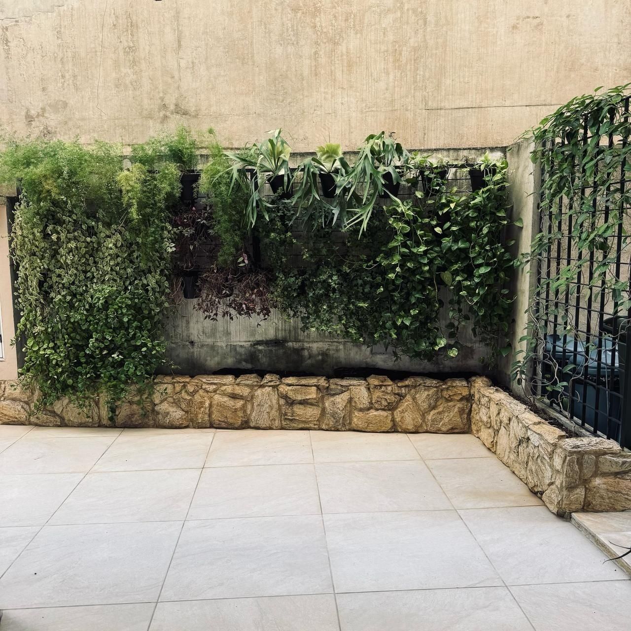 Jardim vertical sobre mureta de pedra no pátio de um prédio