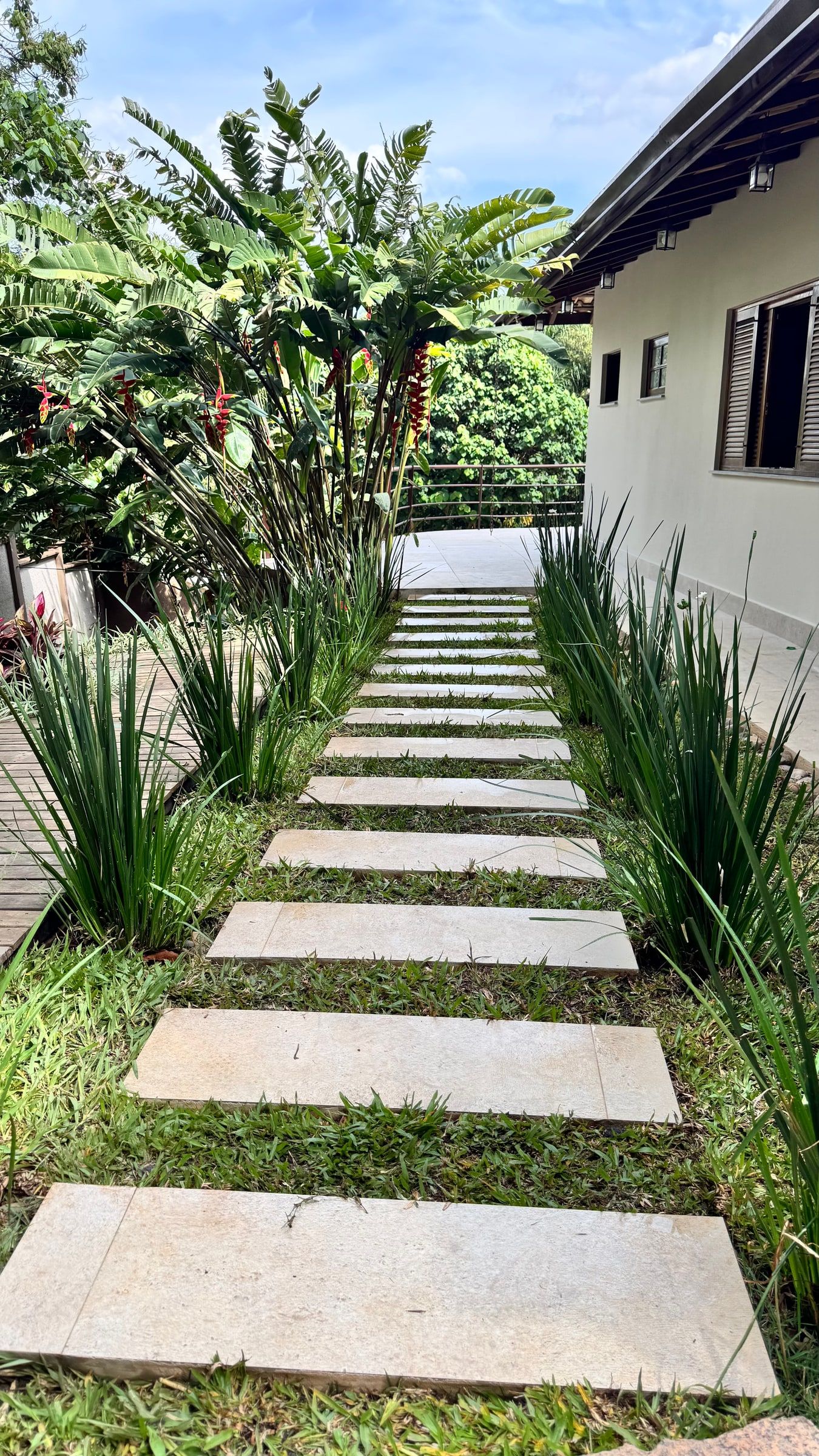 Caminho de pedras entre helicônias e bananeiras-ornamentais até a casa
