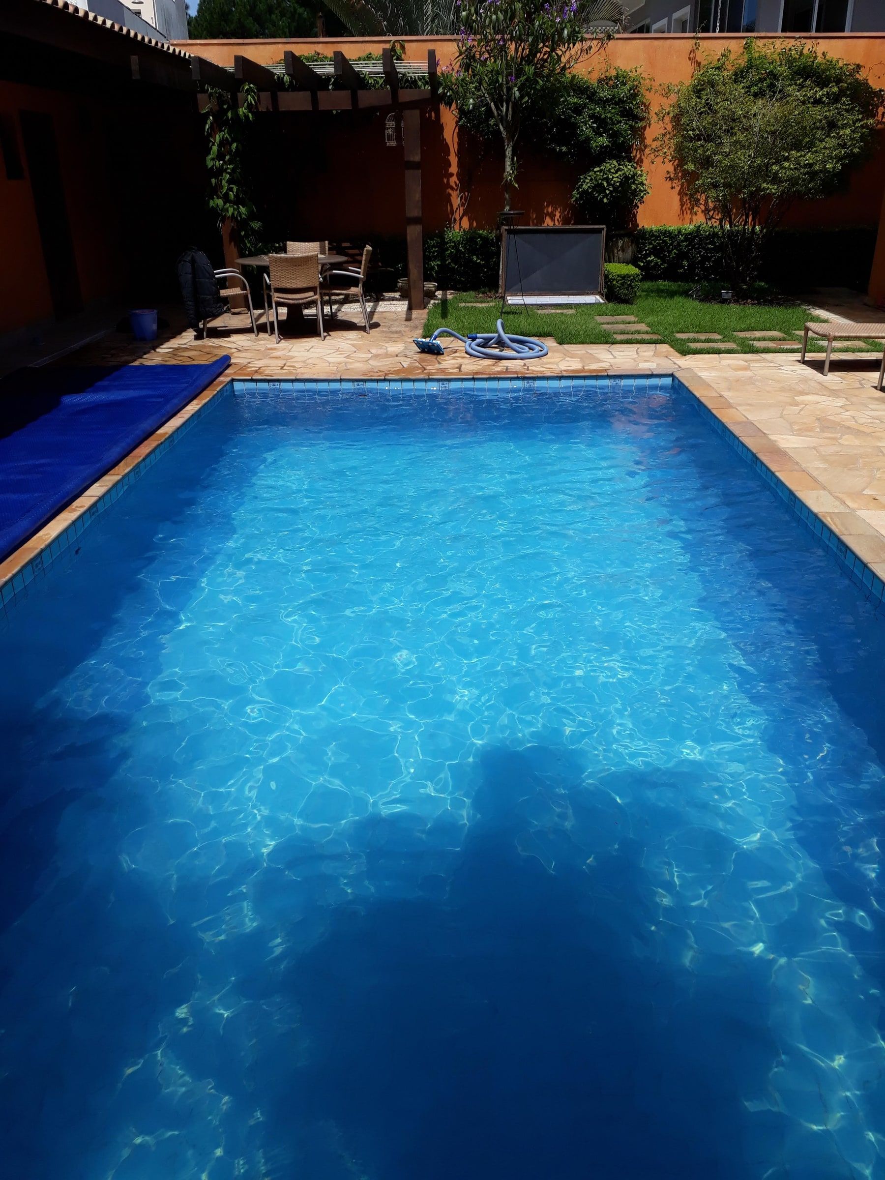 Piscina de casa com deck, pergola de madeira e área de estar ao lado