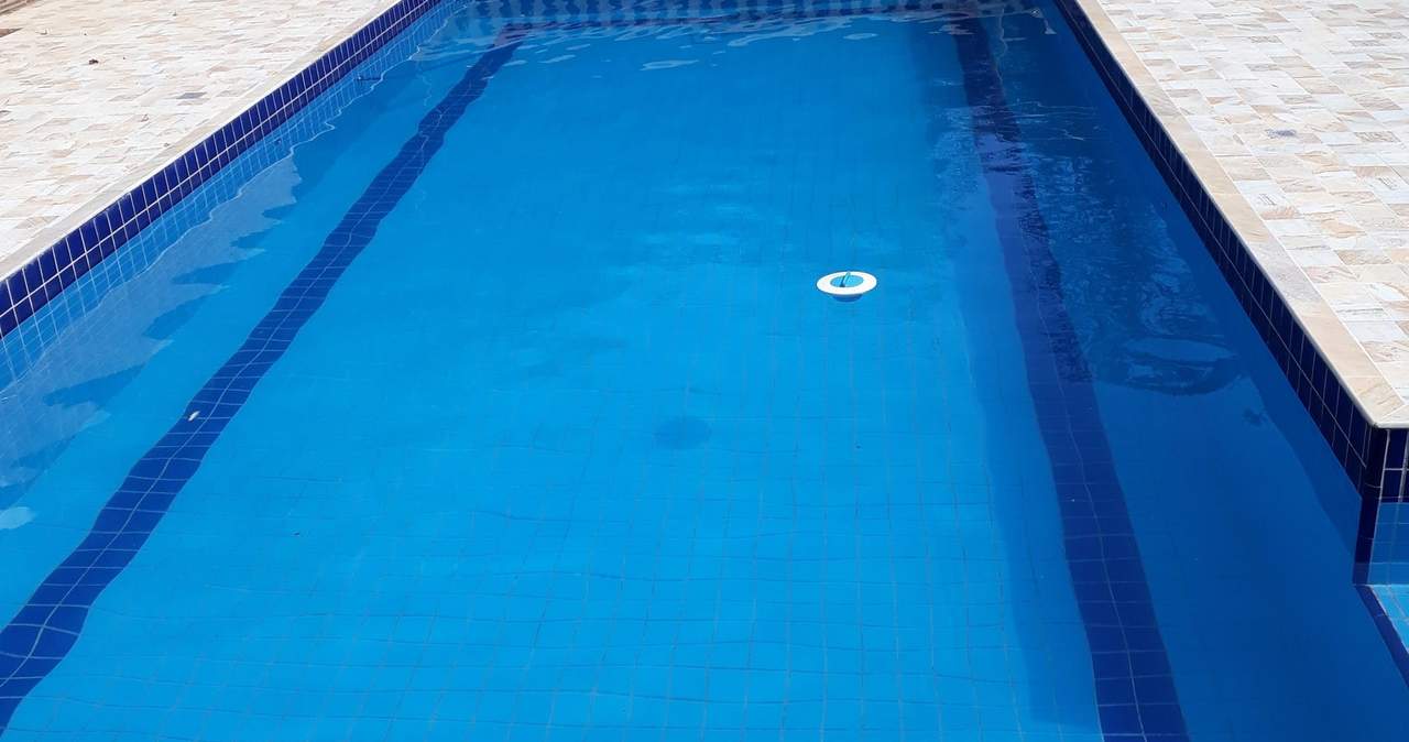 Piscina retangular de água azul e transparente, com bambuzal ao fundo